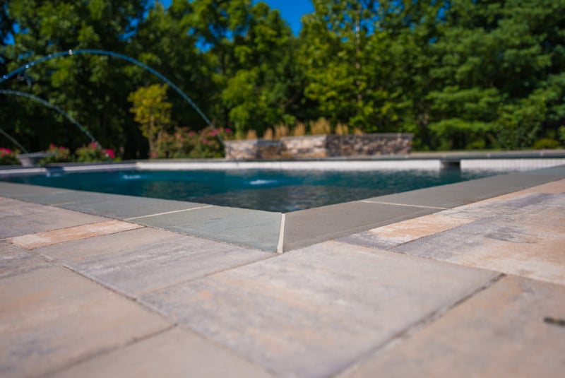 Up-close detail of stone pool coping on rectangular pool by Deckscapes of VA