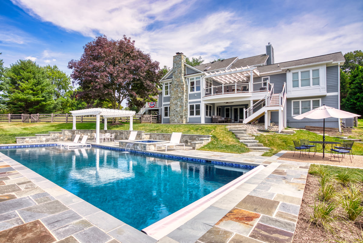 View of backyard in Northern VA with pool, deck, and under deck living space by Deckscapes