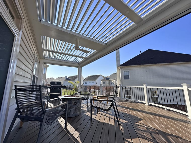 White pergola built on deck with chairs surrounding fireplace beneath by Deckscapes of VA