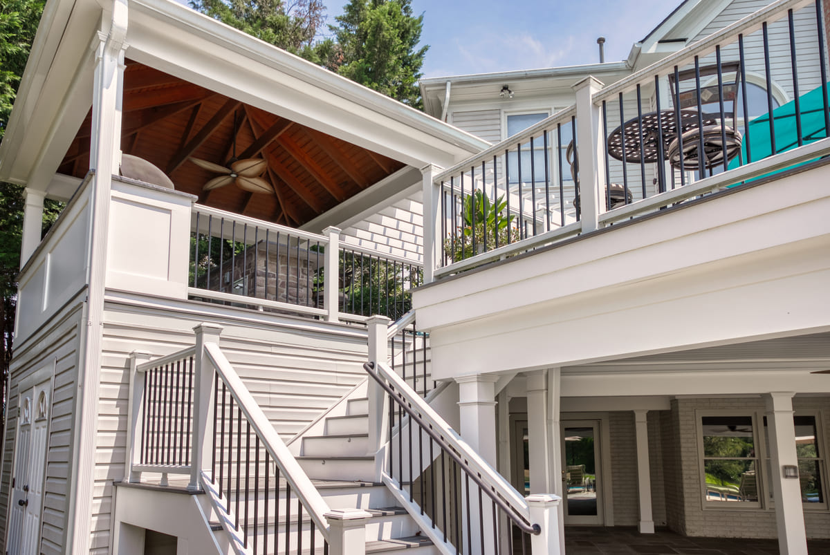 White staircase leading up to multi-level deck and outdoor kitchen by Deckscapes of Virginia