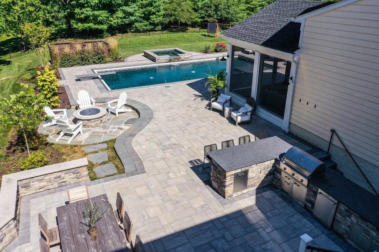 Backyard patio with outdoor kitchen and fireplace walkway to pool