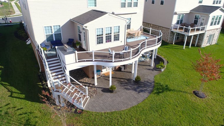Custom raised deck with curved railing and white posts and stairs to patio area