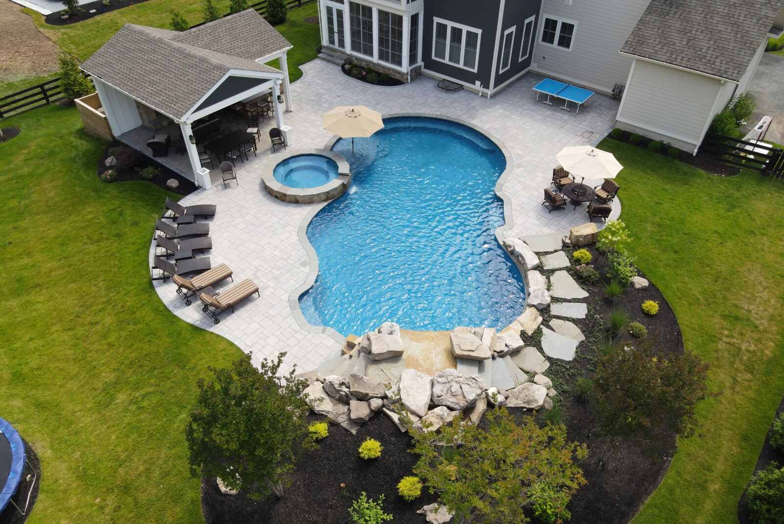 gorgeous aerial pool with hot tub flowing into and garden and lounge area surrounding