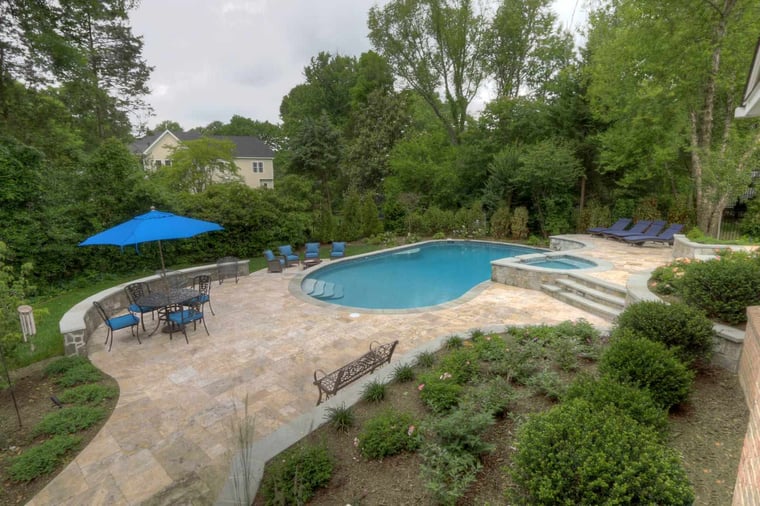 Large flagstone patio near in-ground pool with curved retaining wall