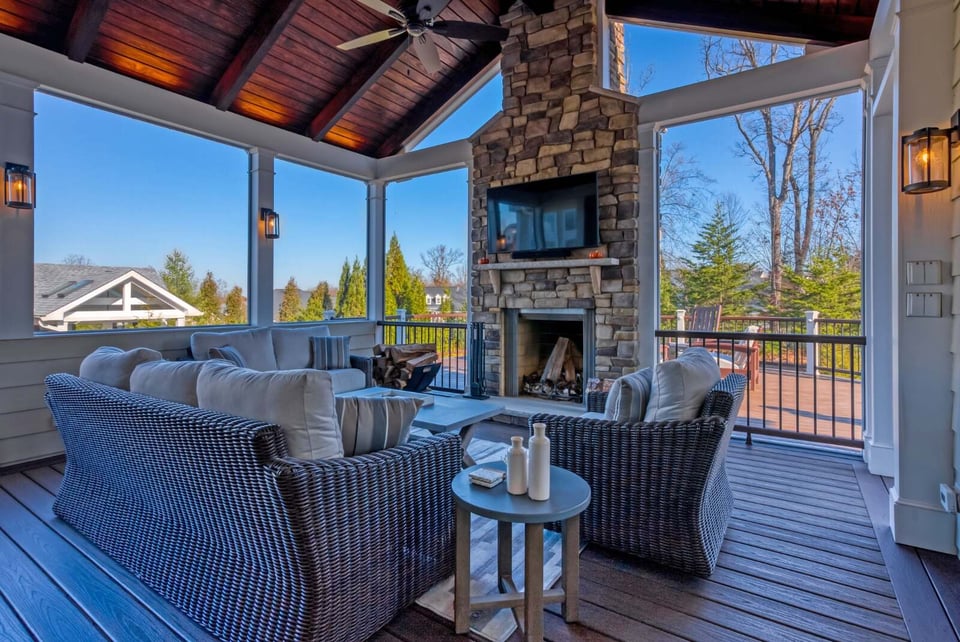 screened in porch with fireplace and stone accent wall with floating tv furniture and ceiling fan