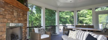 Screened-in porch interior with stone fireplace and black railing