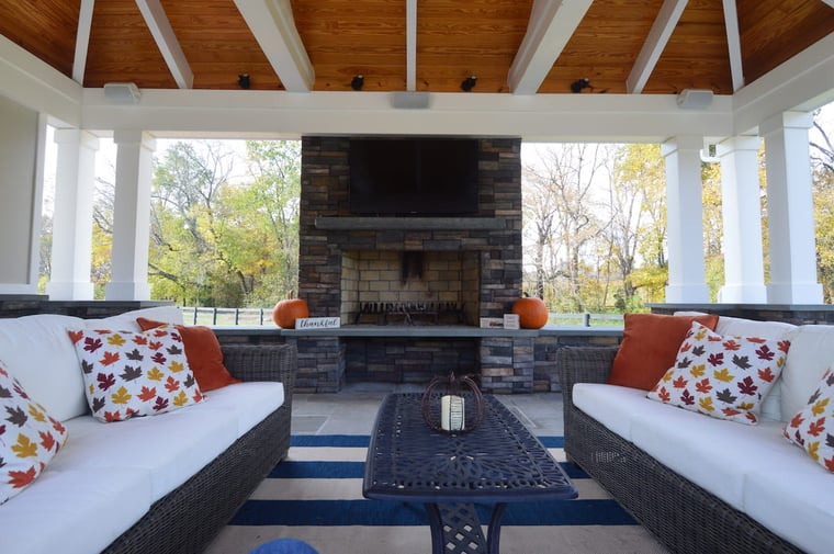 Stone fire place and mounted TV in covered porch with outdoor furniture