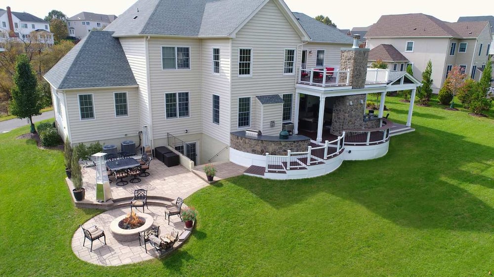 View of deck and patio with fire pit and curved staircase by Deckscapes of Virginia