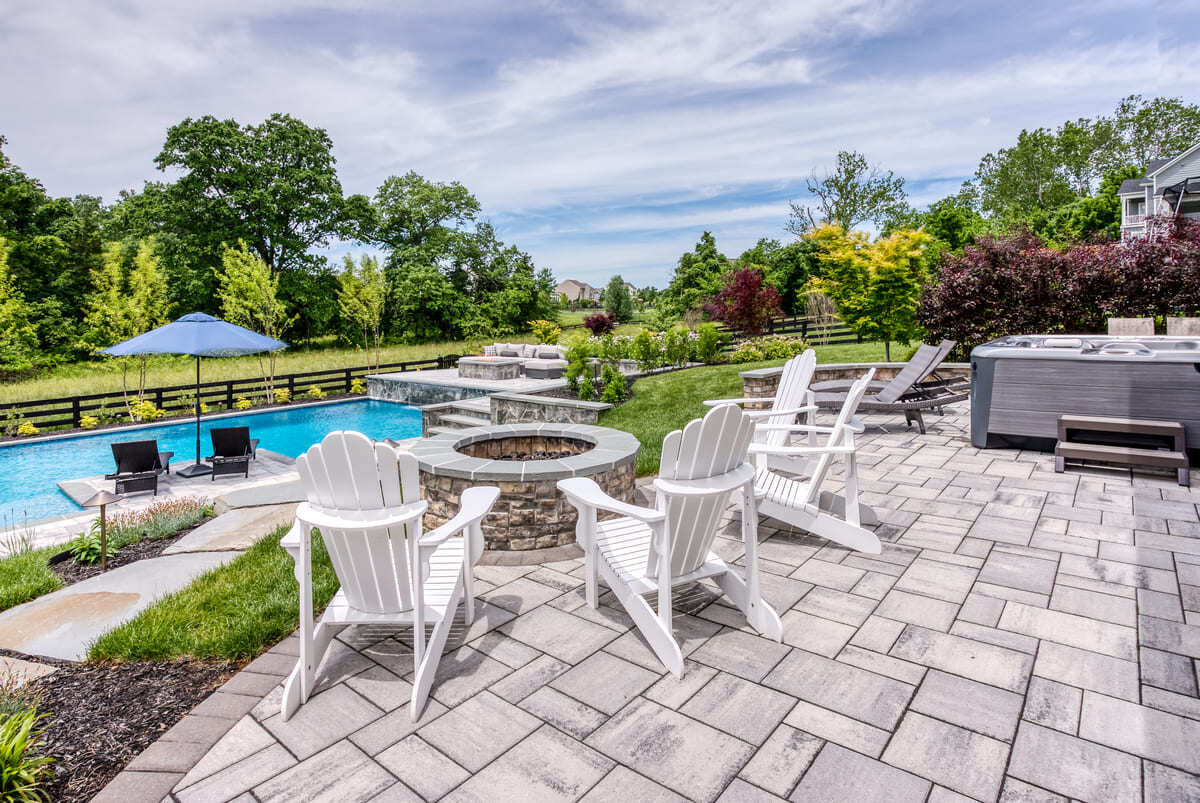 Chairs around firepit on paver patio looking at in ground pool in Northern Virginia