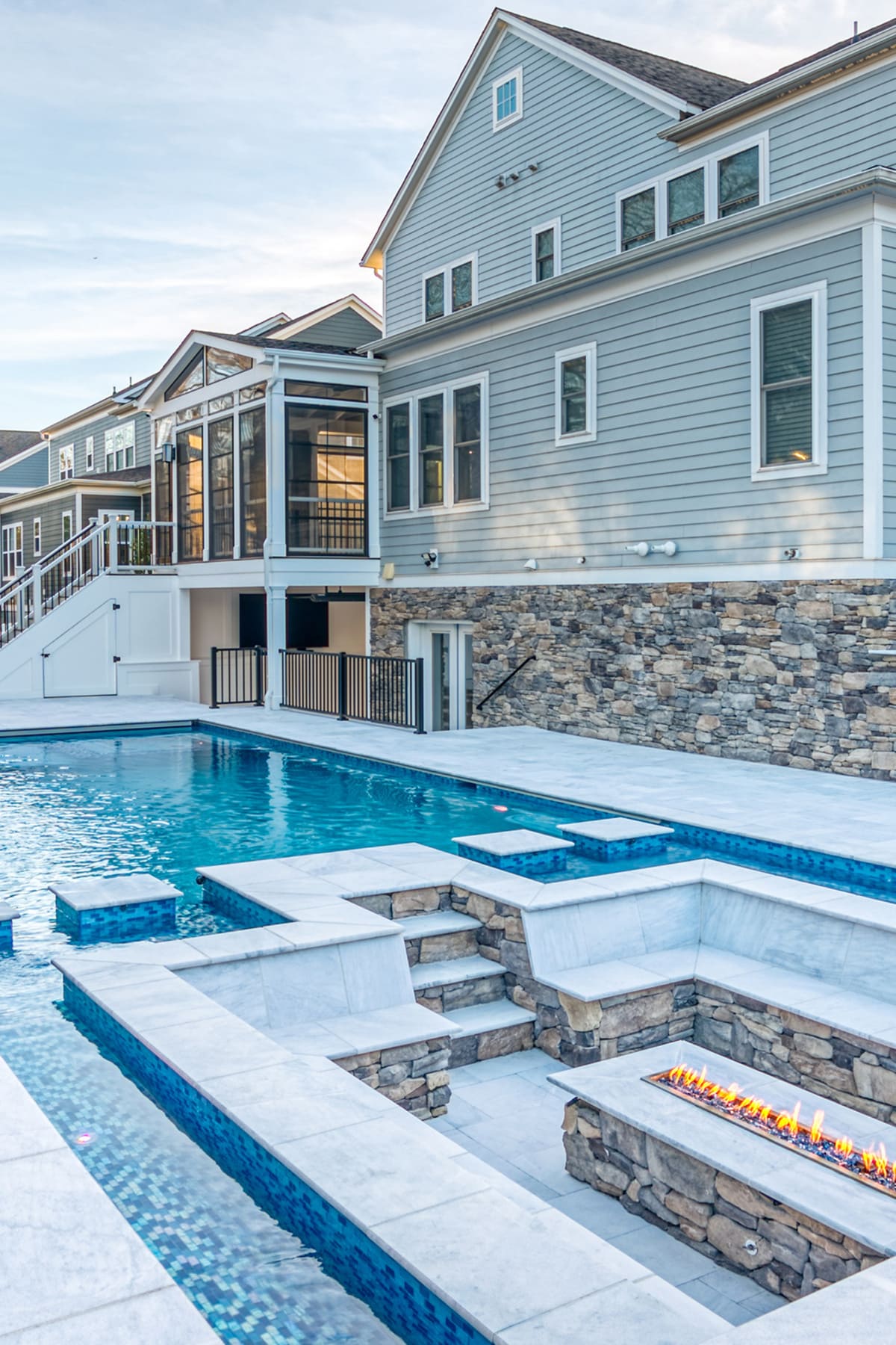 Luxury gunite pool with in-ground seating area and fireplace by Deckscapes of VA