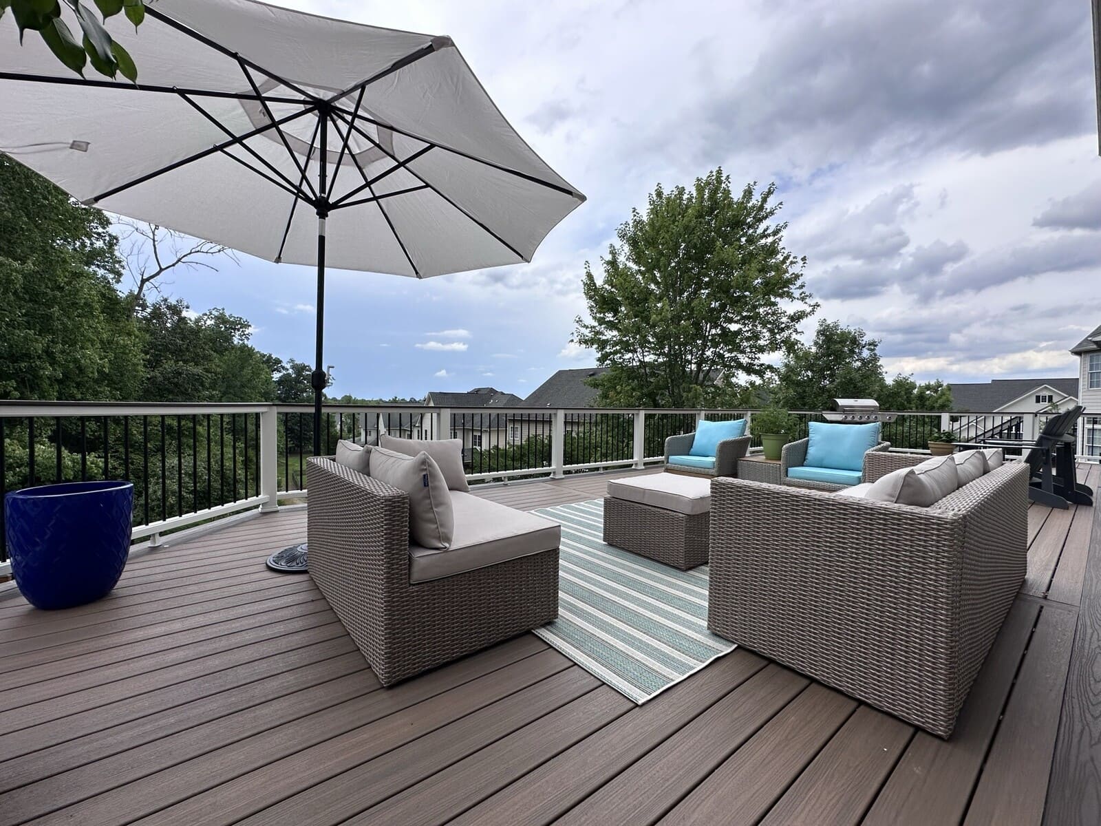 Outdoor furniture and umbrella on raised deck by Deckscapes of Virginia