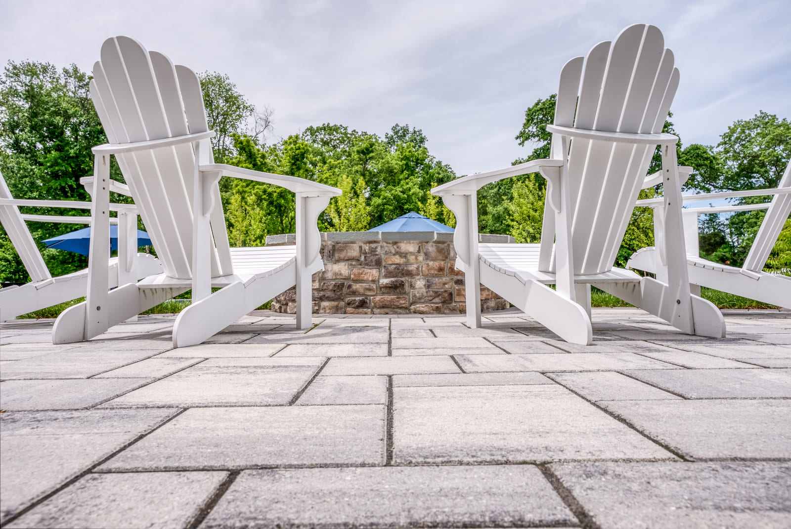 Concrete patio detailing with two white adirondack chairs