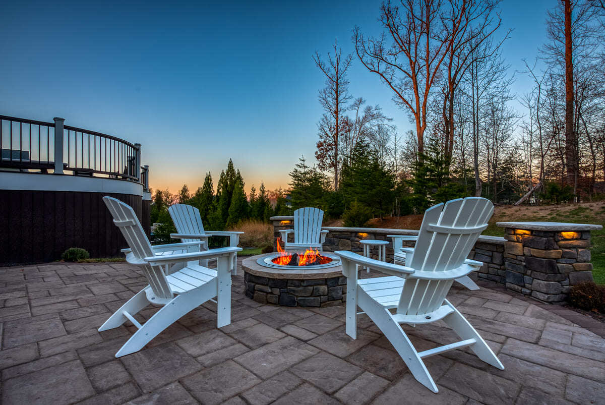 Patio with fireplace and custom lighting in retaining wall by Deckscapes of Virginia