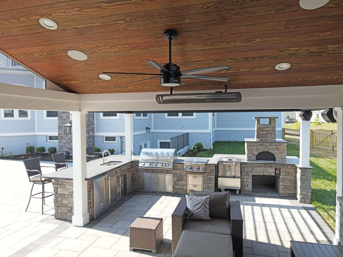 Pool house with fan and heater with attached outdoor kitchen by Deckscapes of Virginia