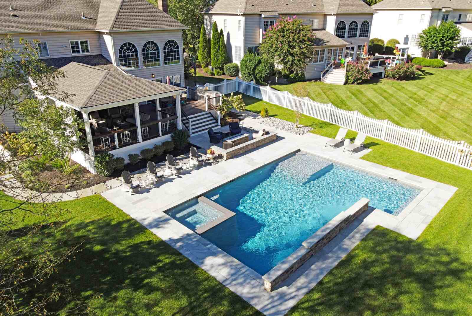 aerial pool with hot tub in corner with stone walkway surrounding